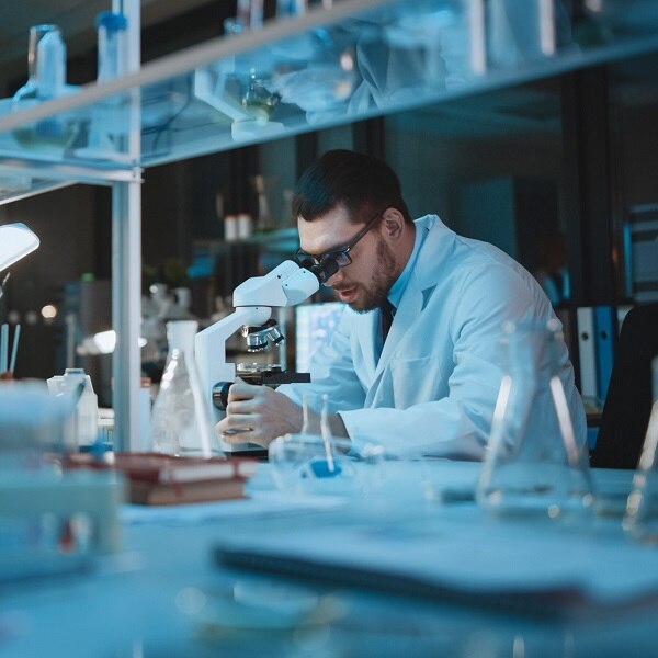 Medical Development Laboratory: Caucasian Female Scientist Looking Under Microscope, Analyzes Petri Dish Sample. Specialists Working on Medicine, Biotechnology Research in Advanced Laboratory