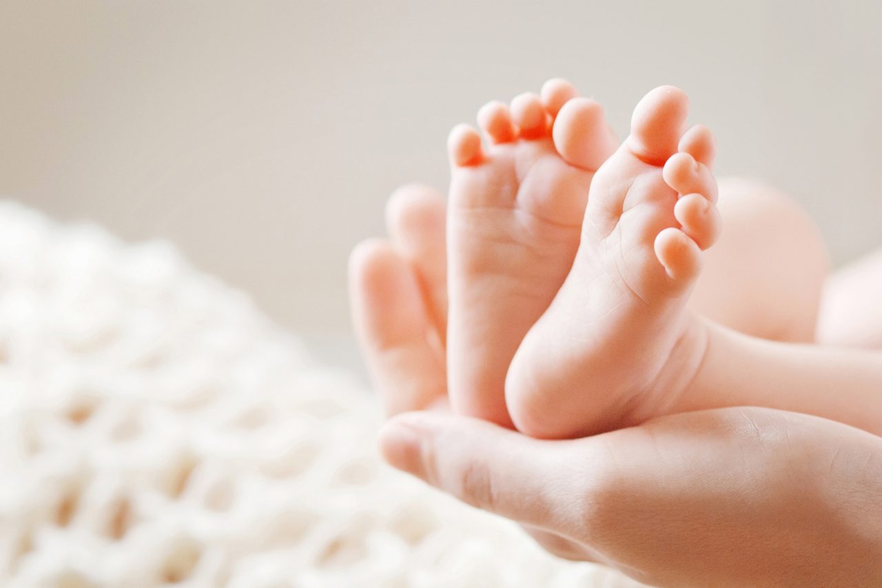 Baby feet in mother hands. Tiny Newborn Baby's feet on female Shaped hands closeup. Mom and her Child. Happy Family concept. Beautiful conceptual image of Maternity