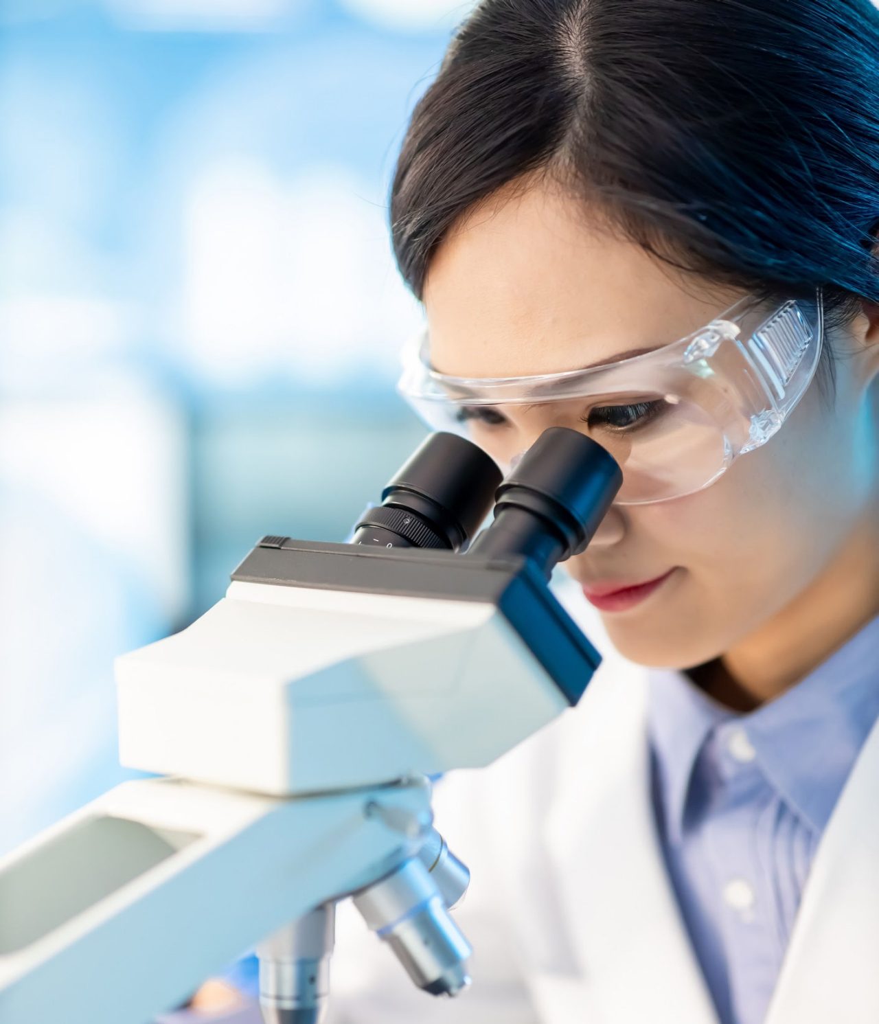 Successful female asian scientist use microscope to check the experiments in the laboratory