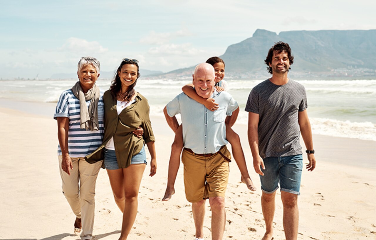 Eine glückliche Familie, die gemeinsam an einem Strand spazieren geht 
