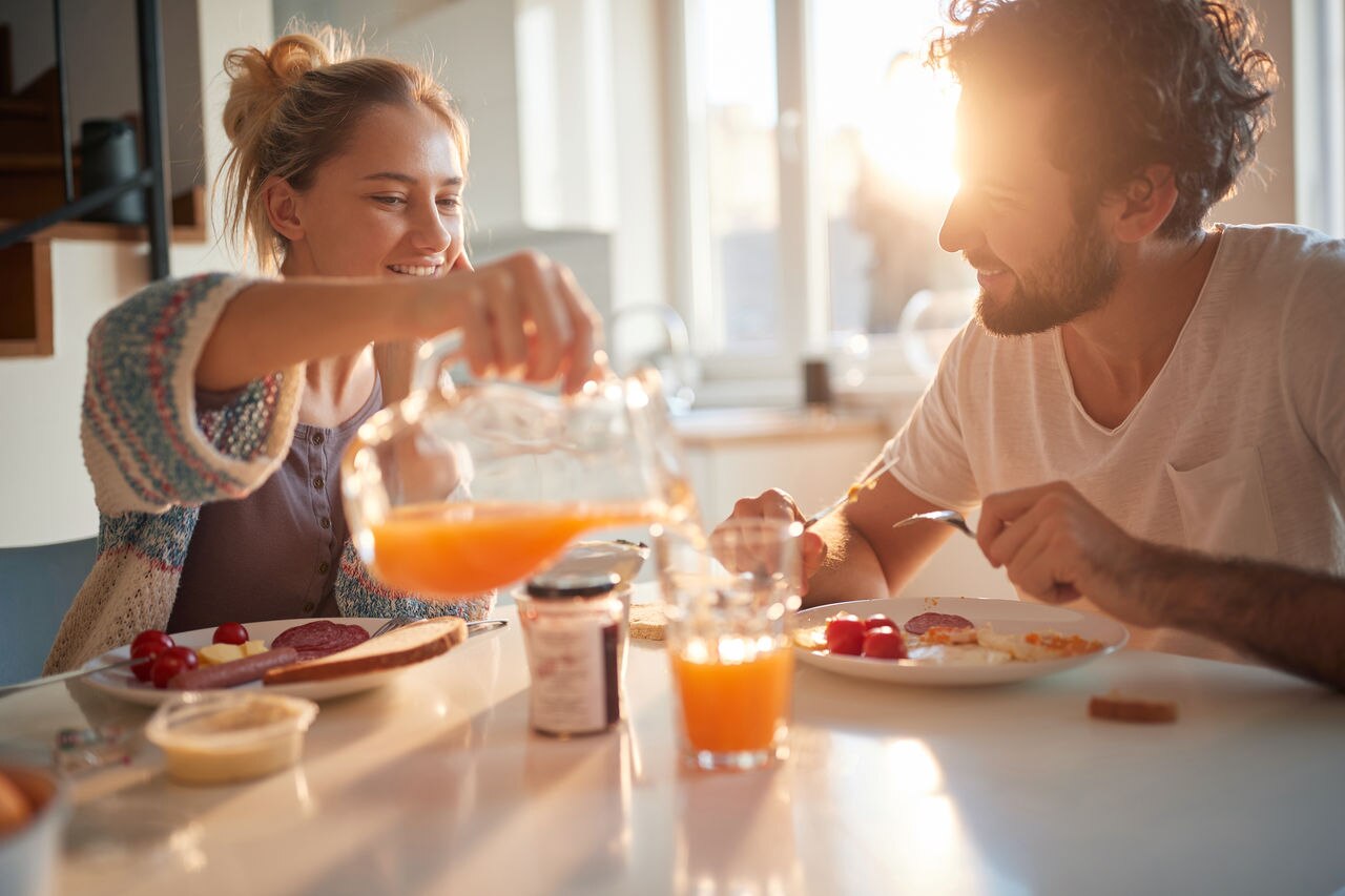 Happy couple having breakfast together in the kitchen