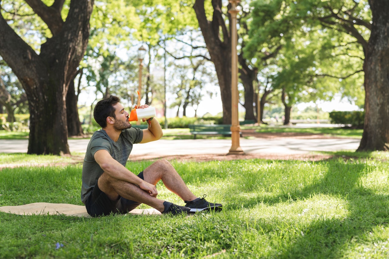 Young man is taking a break from his exercise to make and drink a nutritional protein shake.