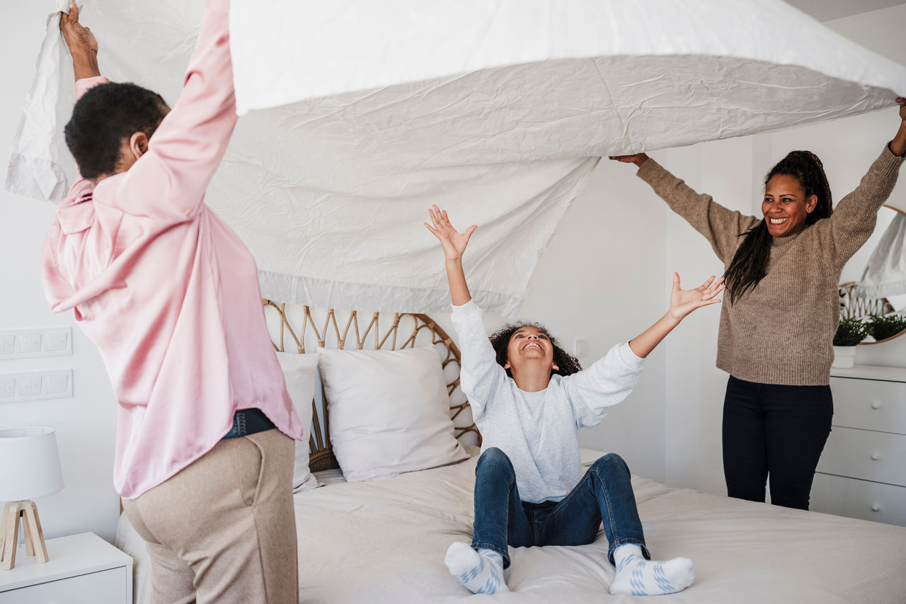Girl having fun with mother and grandmother in bedroom at home
