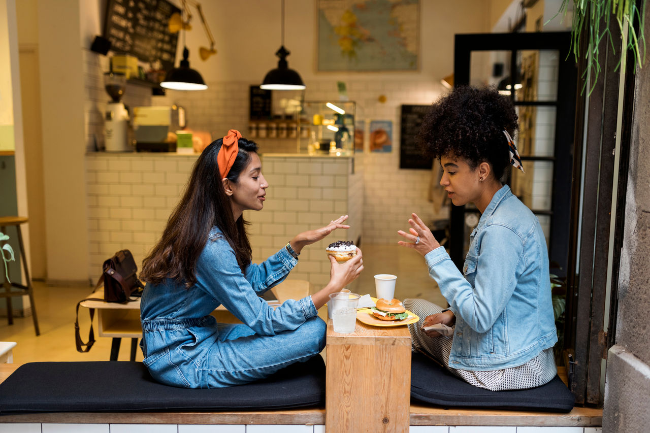 Women talking about food while sitting by window at cafe; Shutterstock ID 1908528694; purchase_order: TTH Brief (2); job: ; client: ; other: 