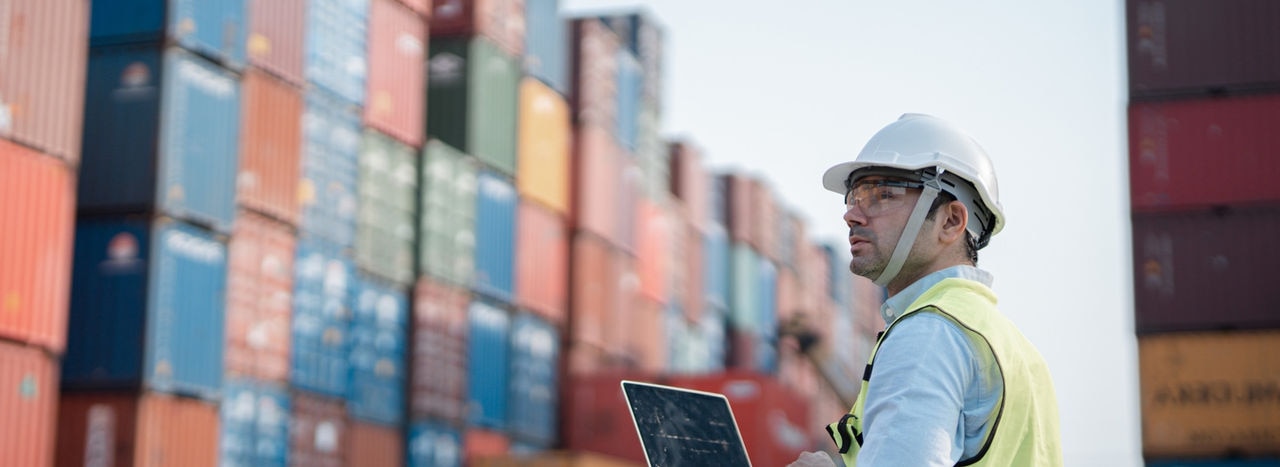 Male engineer working at Containers yard. Cargo port storage for transportation and trading.