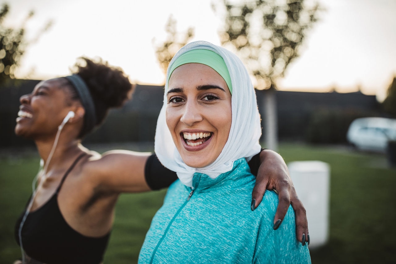 Two young women, different ethnicity ,exercisng outdoor. They are wearing sport clothing.
Getting ready for training.