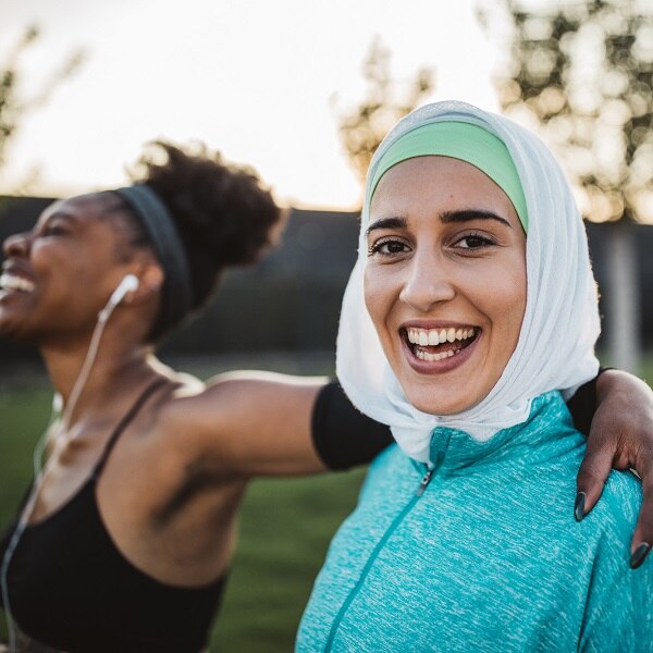 Two young women, different ethnicity ,exercisng outdoor. They are wearing sport clothing.
Getting ready for training.