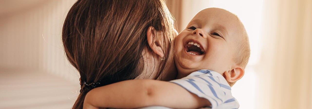 Two people, mother hugging her little son at home.