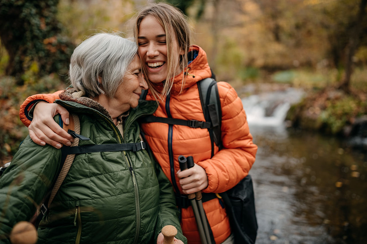 Senior women and her granddaughter hiking on mountain, walking through forest
