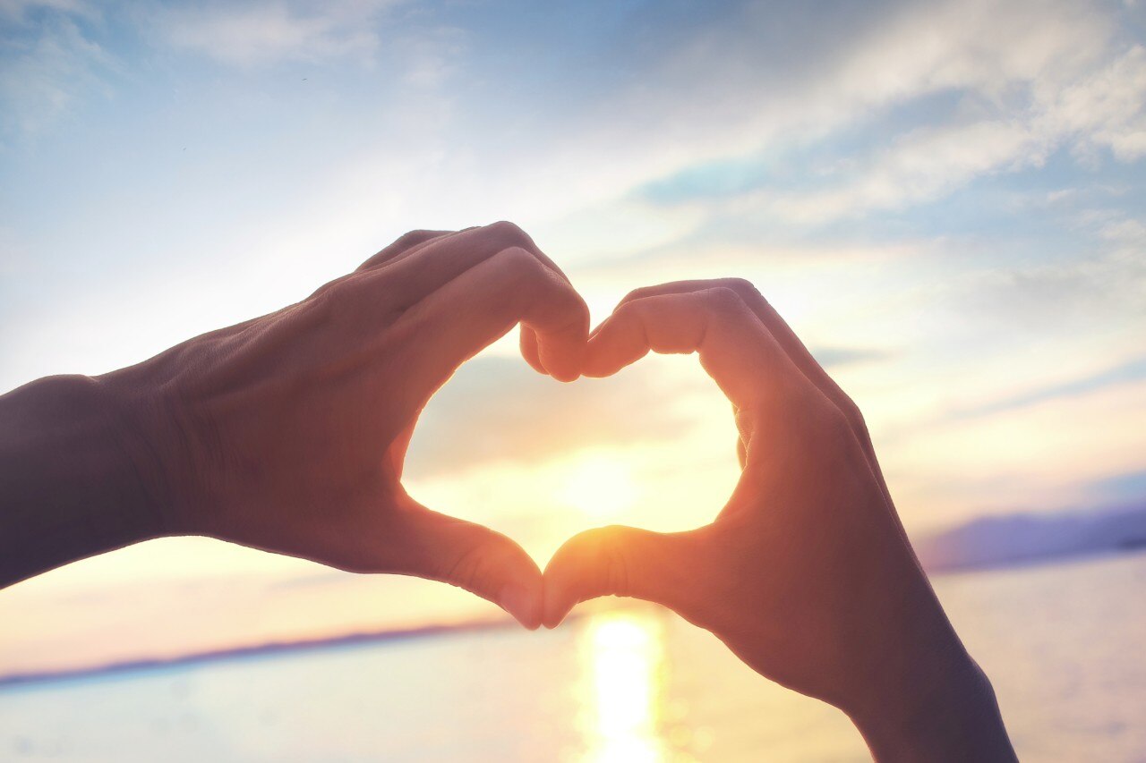 Heart shape made with hands at sunset