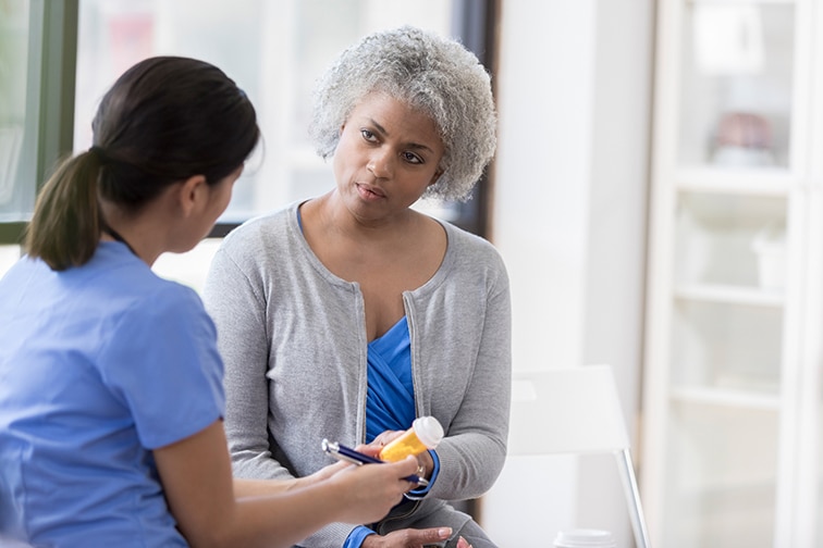A senior woman sits beside her doctor.