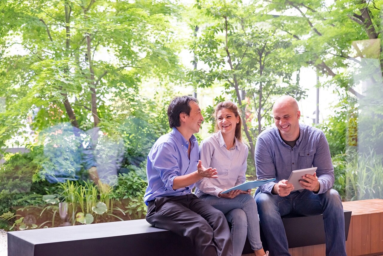 Two businessmen and businesswoman are working in front of window at entrance hall of office buildings