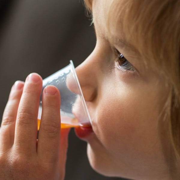 Cute little boy drinking cough syrup from a dose at home. Copy space.