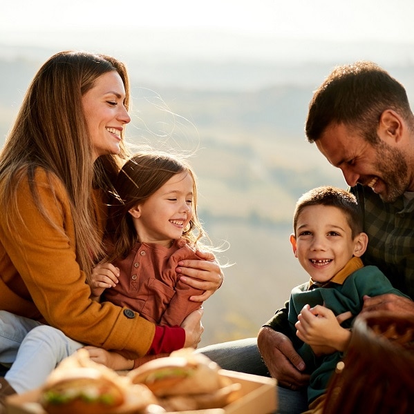 Cheerful parents having fun with their kids on picnic in autumn day.
