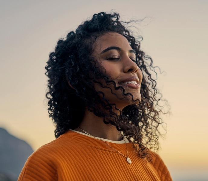 Happy woman in nature, sunset sky peace and smile breathing co2. Wellness beauty, clear outdoor sky and
fresh wave of calm. Eyes closed, asthma treatment air and girl with curly hair relaxed face.
