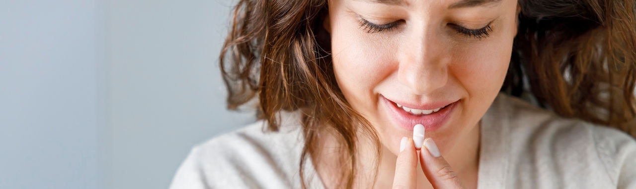 Smiling young woman taking medication at home