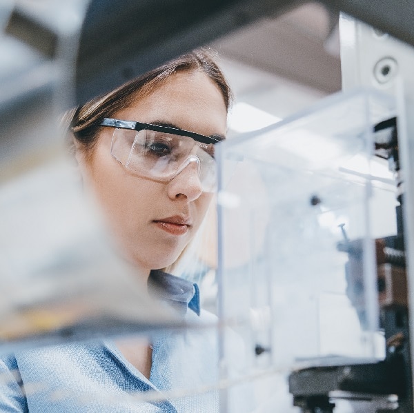 Professional young industrial factory woman employee working with machine parts putting, checking and testing industrial equipments cables in large Electric electronics wire and cable manufacturing plant factory warehouse