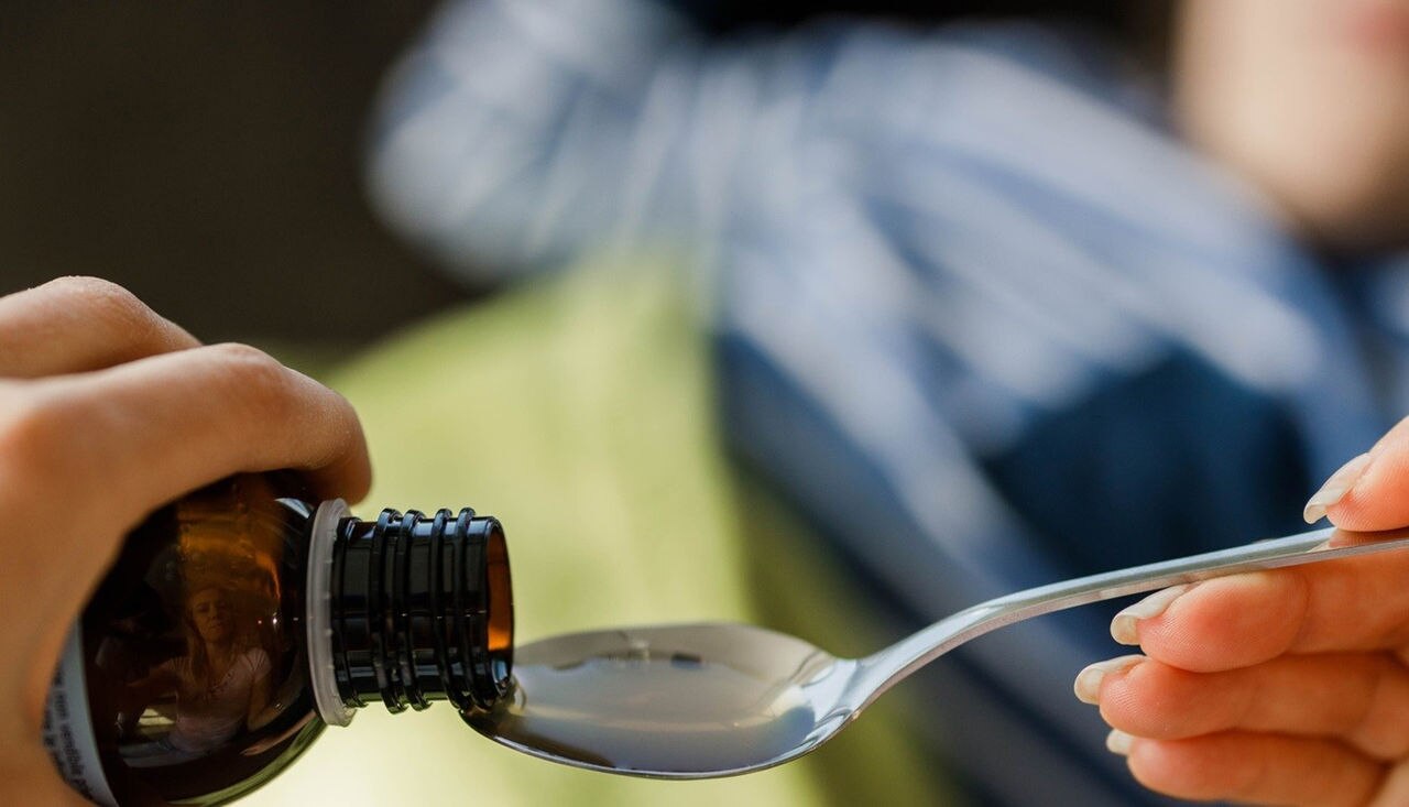 Person serving medicine in a spoon