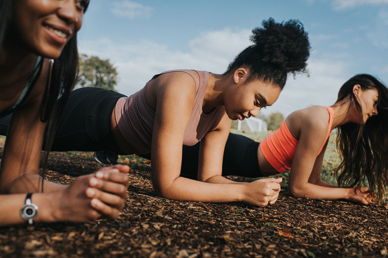 Three fit woman in bootcamp. They put in a lot of effort by planking side-by-side. Space for copy.