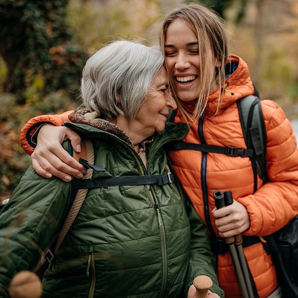 Senior women and her granddaughter hiking on mountain, walking through forest