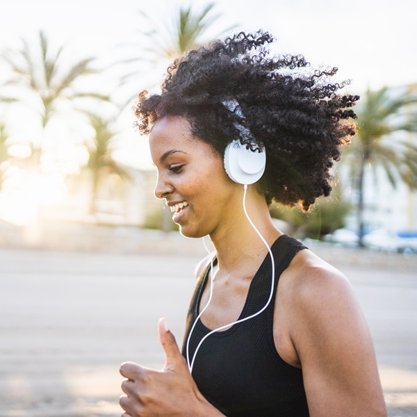 Black woman with afro hair runs listening to music on the beach; Shutterstock ID 2123931209; purchase_order: P&B Loop 1&2(26)-1*.16.01.2024; job: ; client: ; other: 