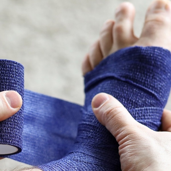 Man pulls stretch on his leg with elastic bandage. Prevents repeated injury. Uniform compression in all areas for foot massage effect. Increase blood circulation and relieve pain