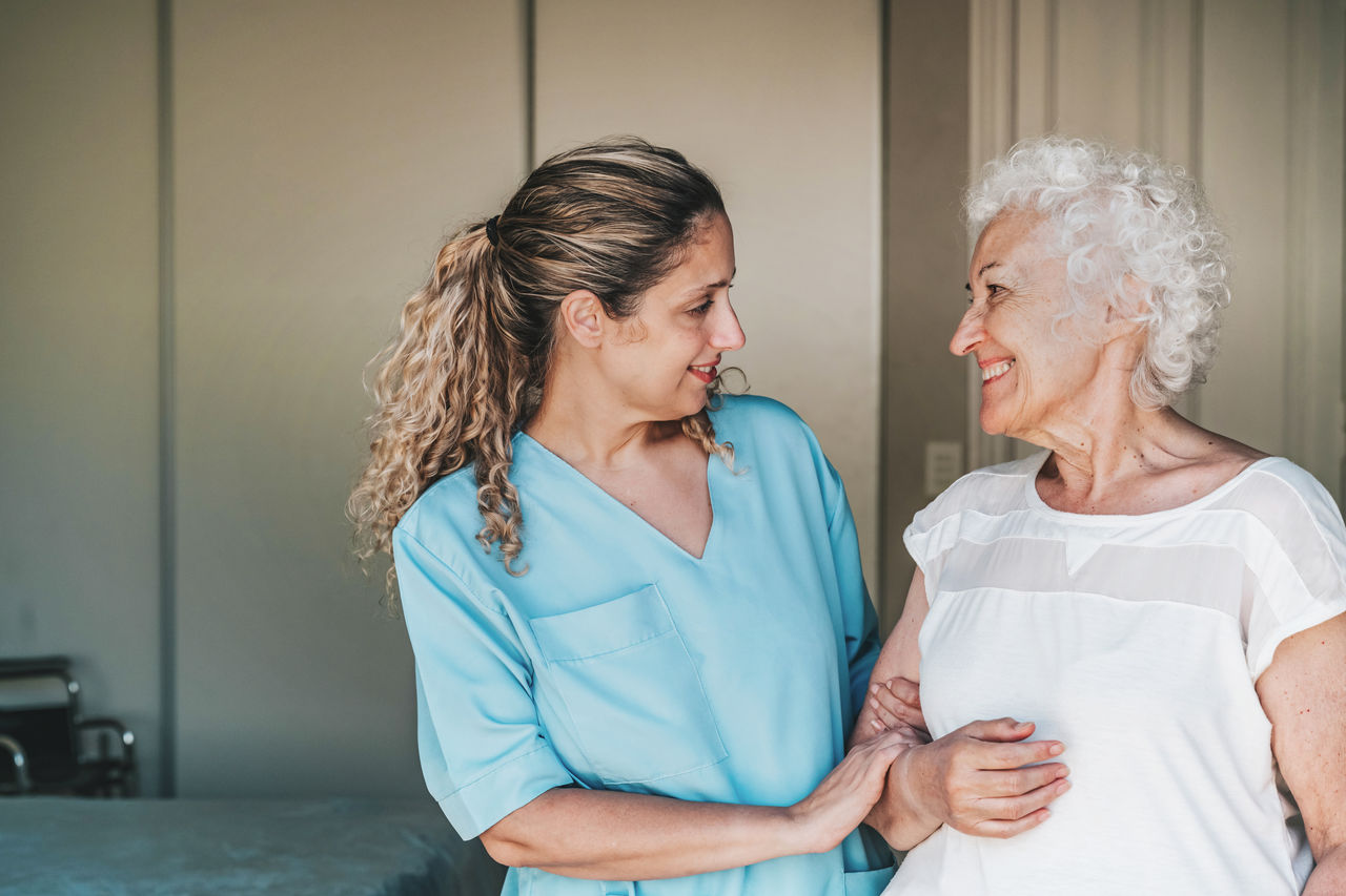 young nurse standing close to female senior patient