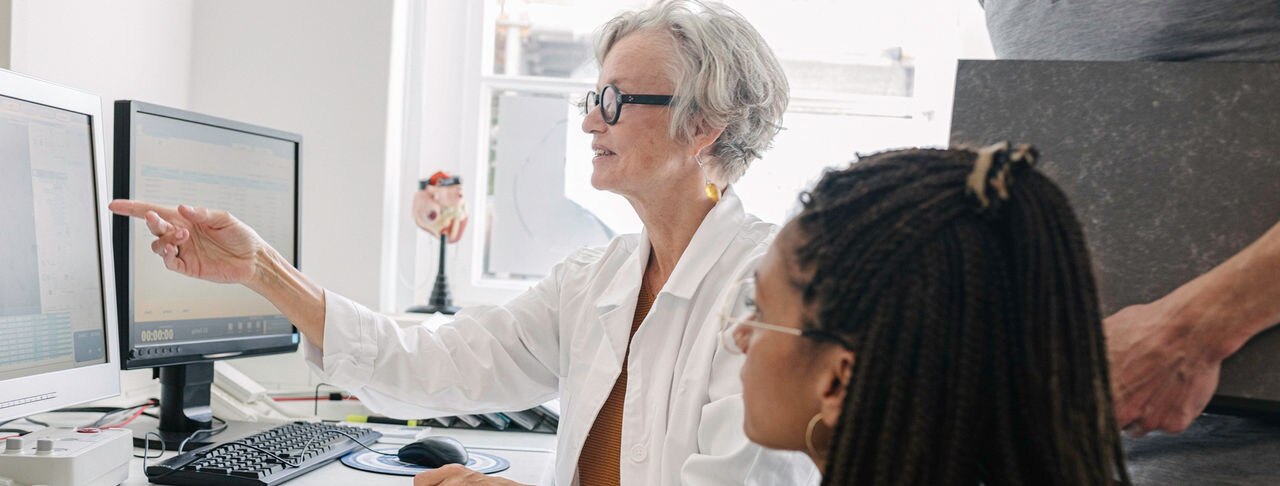 Doctors talking to MRI technicians about Magnetic Resonance Images MRI while pointing at computer screens.