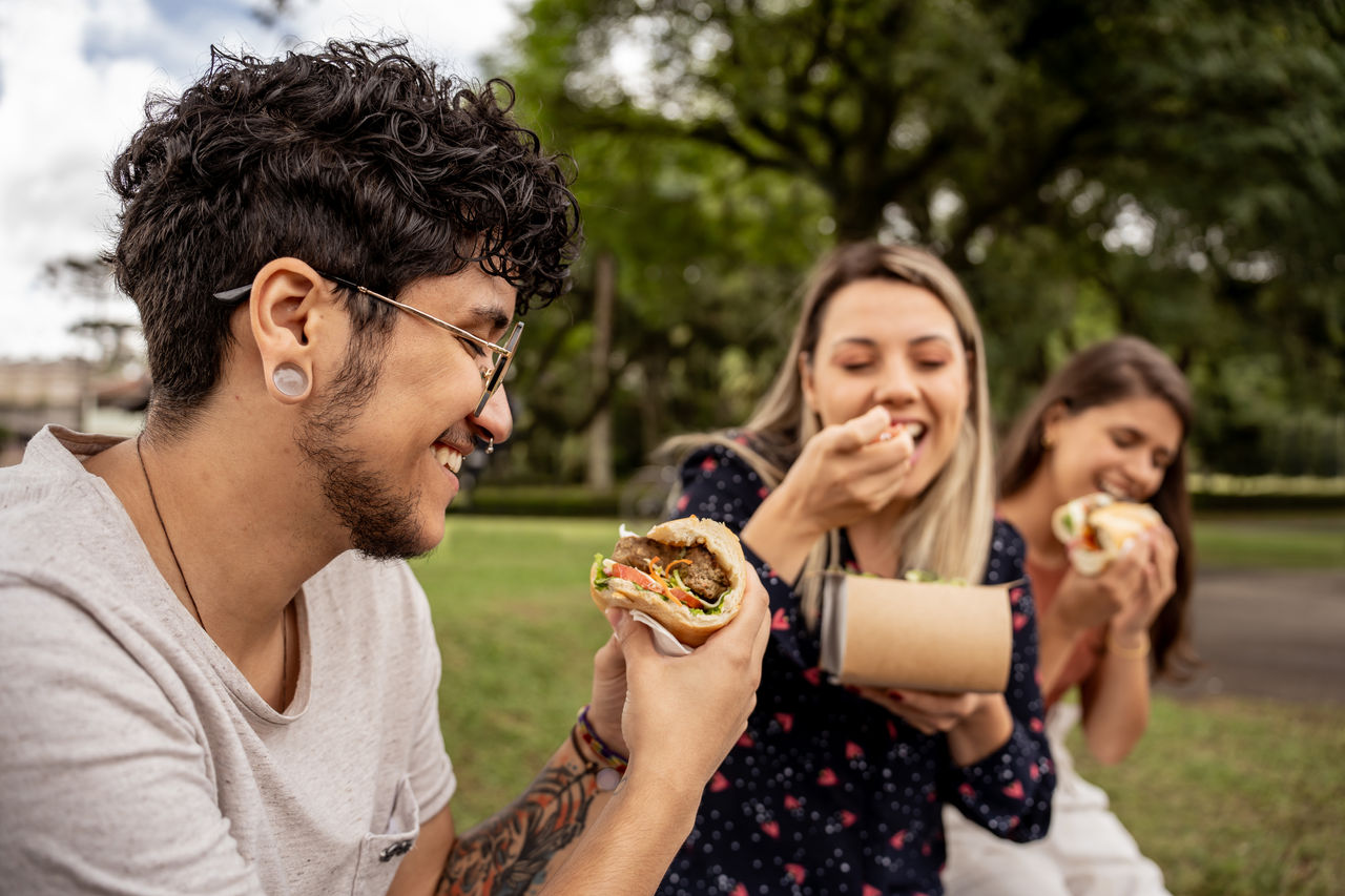 Three friends eating healthy food in the park