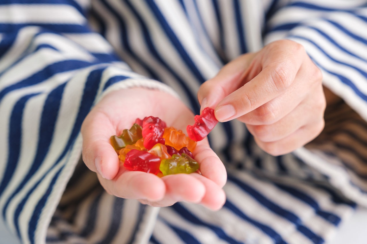 Closeup image of a woman holding and picking a jelly gummy bear