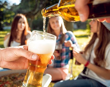 Cheerful friends on picnic in the park. Drinking beer