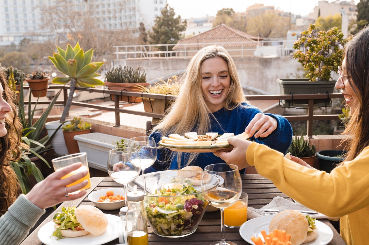 Multiracial friends having fun eating and drinking vegan food at patio restaurant - Focus on center girl face