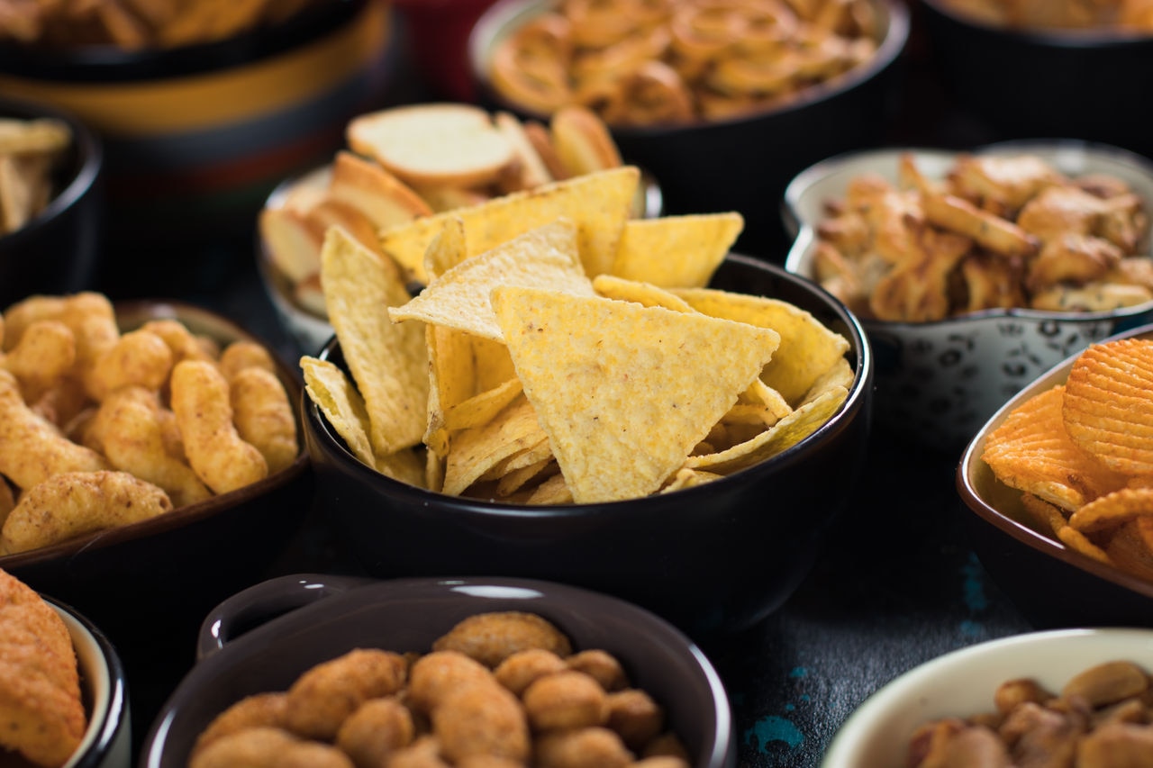 Salty snack including peanuts, potato chips and pretzels served as party food in bowls