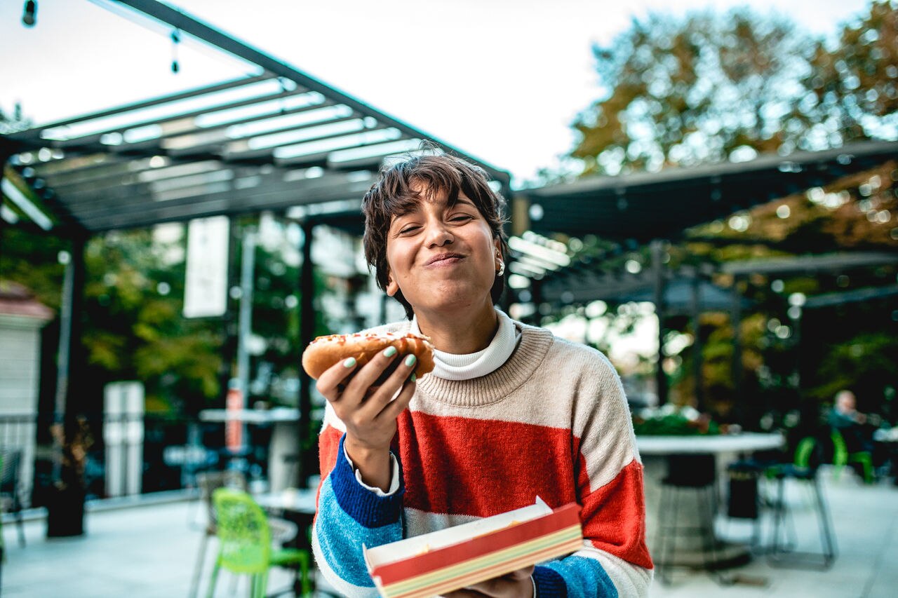 a young girl holds a fast food meal in her hand while she laughs and looks at the camera