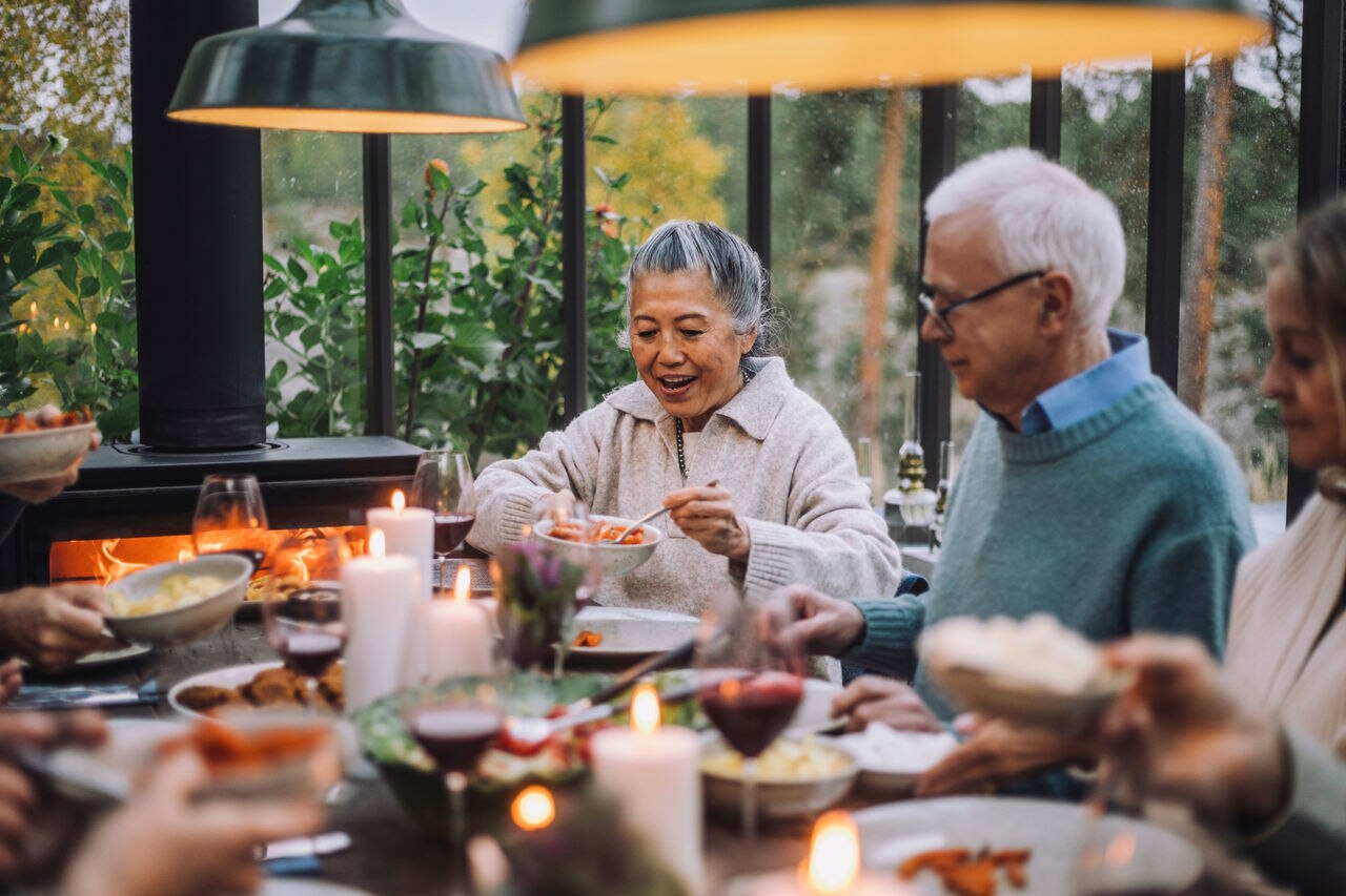 Senior woman serving food to male friend at dinner party; Shutterstock ID 2281291051; purchase_order: Masterbrand - Loop 4; job: ; client: ; other: 