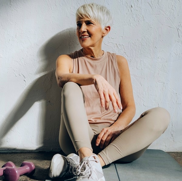 Happy woman in sportswear looking away while resting after home workout training.