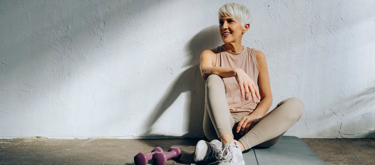 Happy woman in sportswear looking away while resting after home workout training.