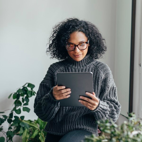 Young woman wearing glasses watching something on her digital tablet (copy space).