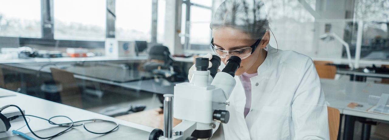 Young scientist working on microscope in laboratory