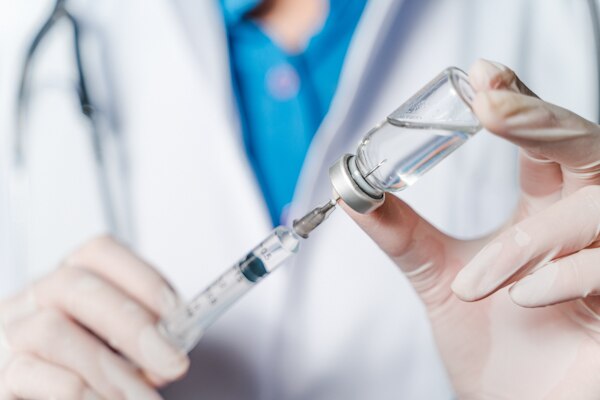 The doctor holding a syringe with Covid-19 vaccines in glass bottle. Covid-19 corona virus treatment concept.