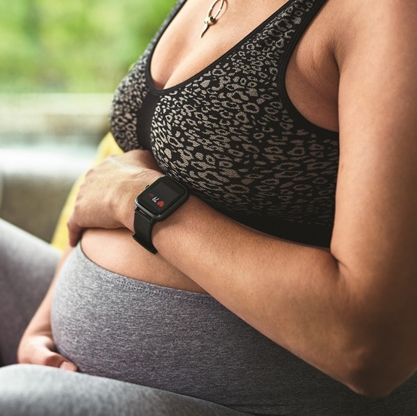 Mid-section of mature woman relaxing wearing sports bra and leggings, embracing belly