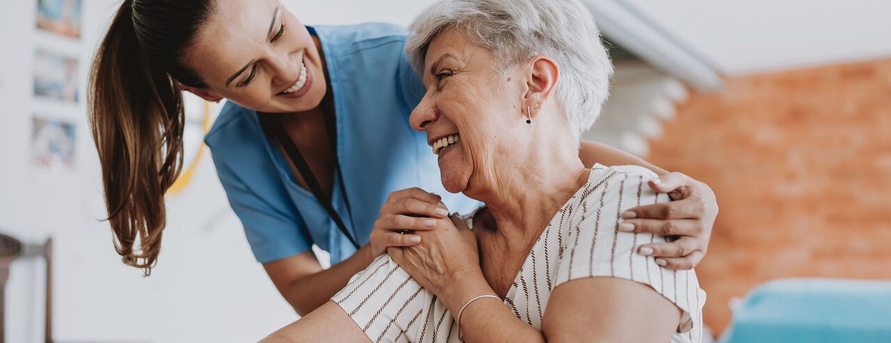 Home care healthcare professional hugging senior patient