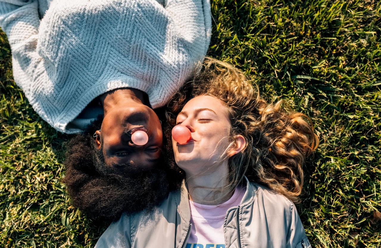 Asturias, Spain, two best friends making a bubble gum lying on the grass