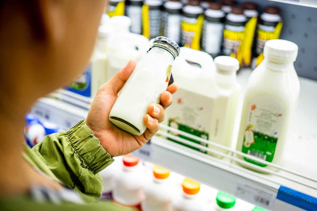 Woman's hand buying milk in the supermarket. Woman choosing milk in dairy product department.