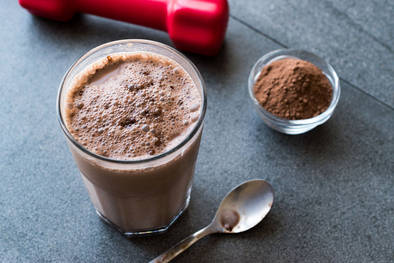 Chocolate Protein Shake Smoothie with Whey Protein Powder and Red Dumbbells. Sports Drink