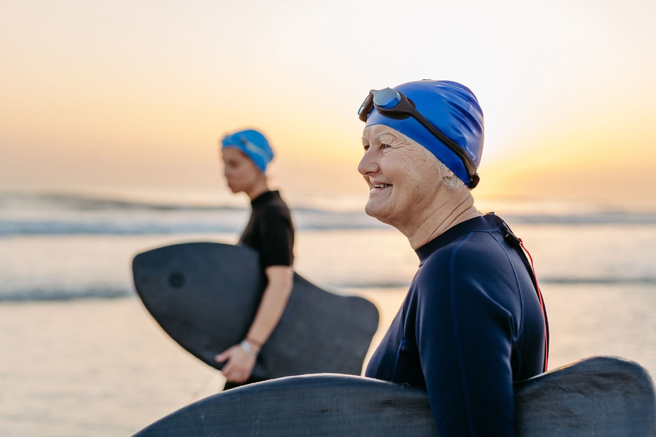 Daughter with her elder mother in neoprene enjoying time at ocean, trying to surfing.