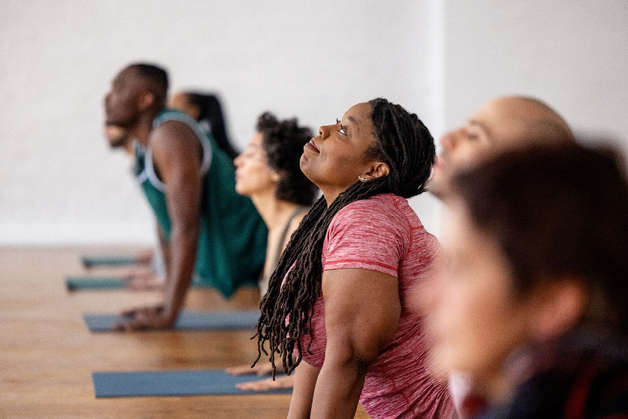 Group of men and women practicing yoga lessons. Diverse group of people in sportswear doing stretching yoga workouts in a fitness studio.