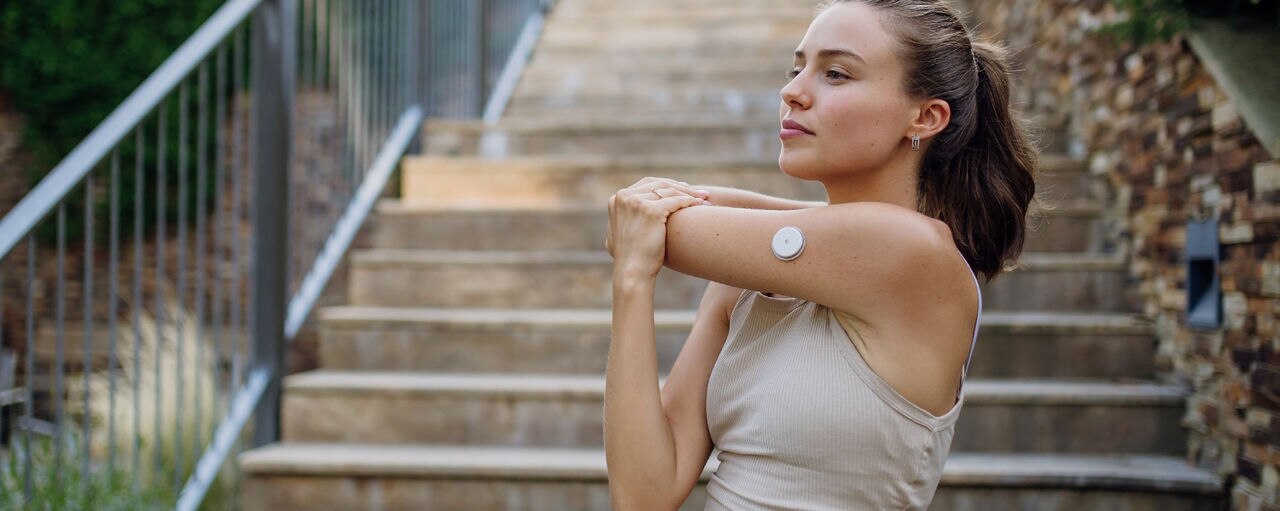 Beautiful diabetic woman preparing for outdoor run in the city. Young woman wearing an insulin pump during exercising. Concept of exercise and diabetes.