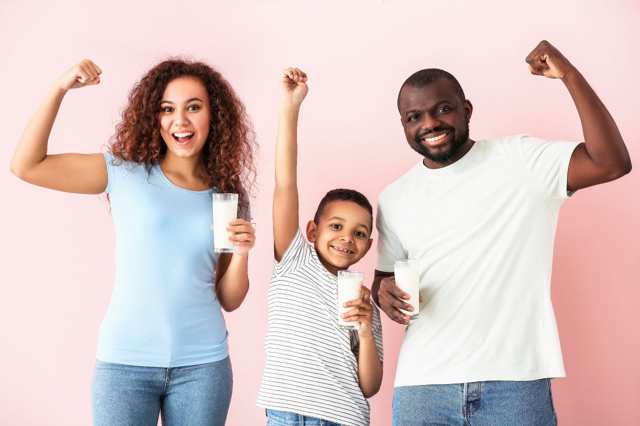 African-American family with milk on color background