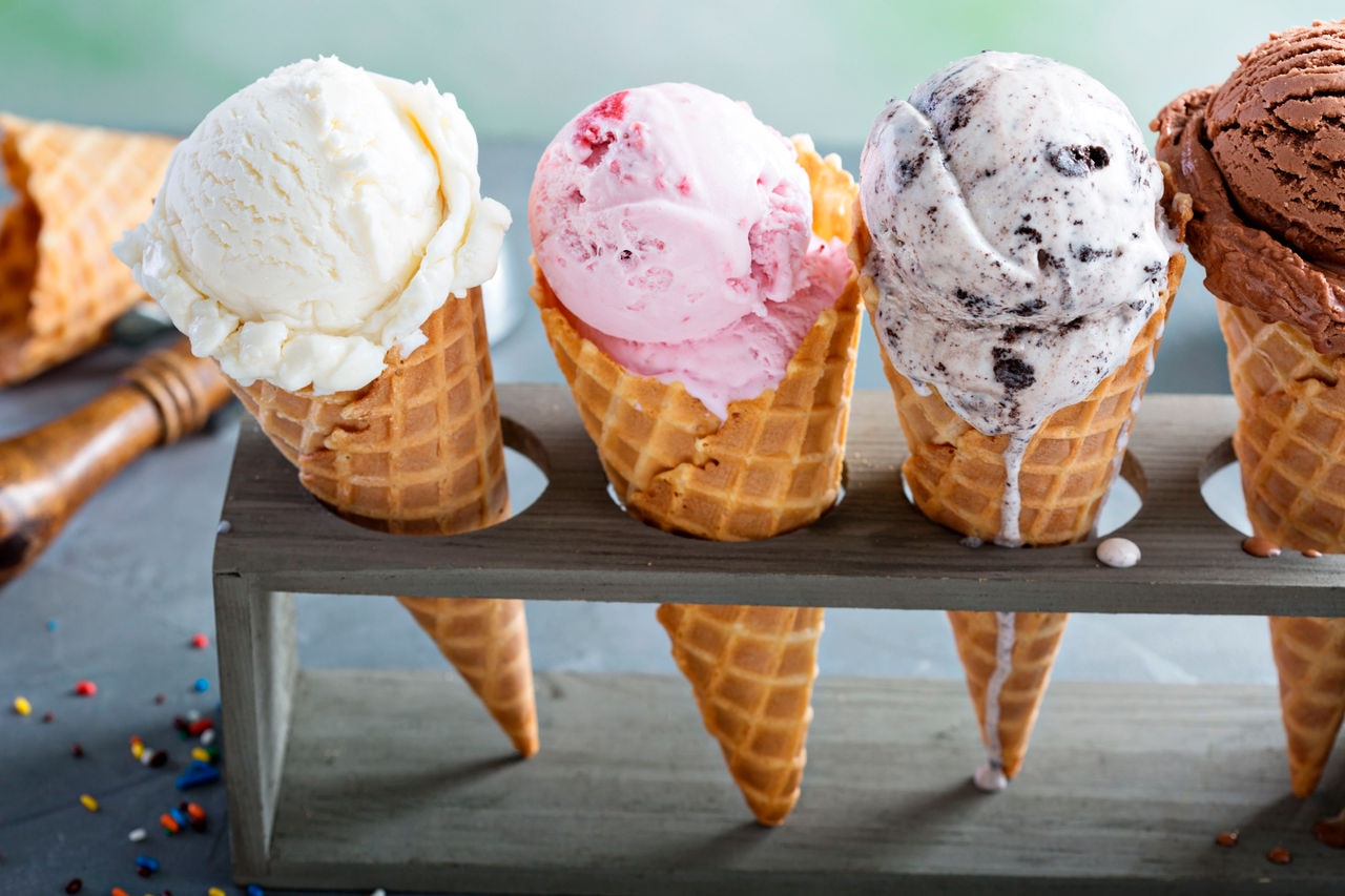 Variety of ice cream scoops in cones with chocolate, vanilla and strawberry